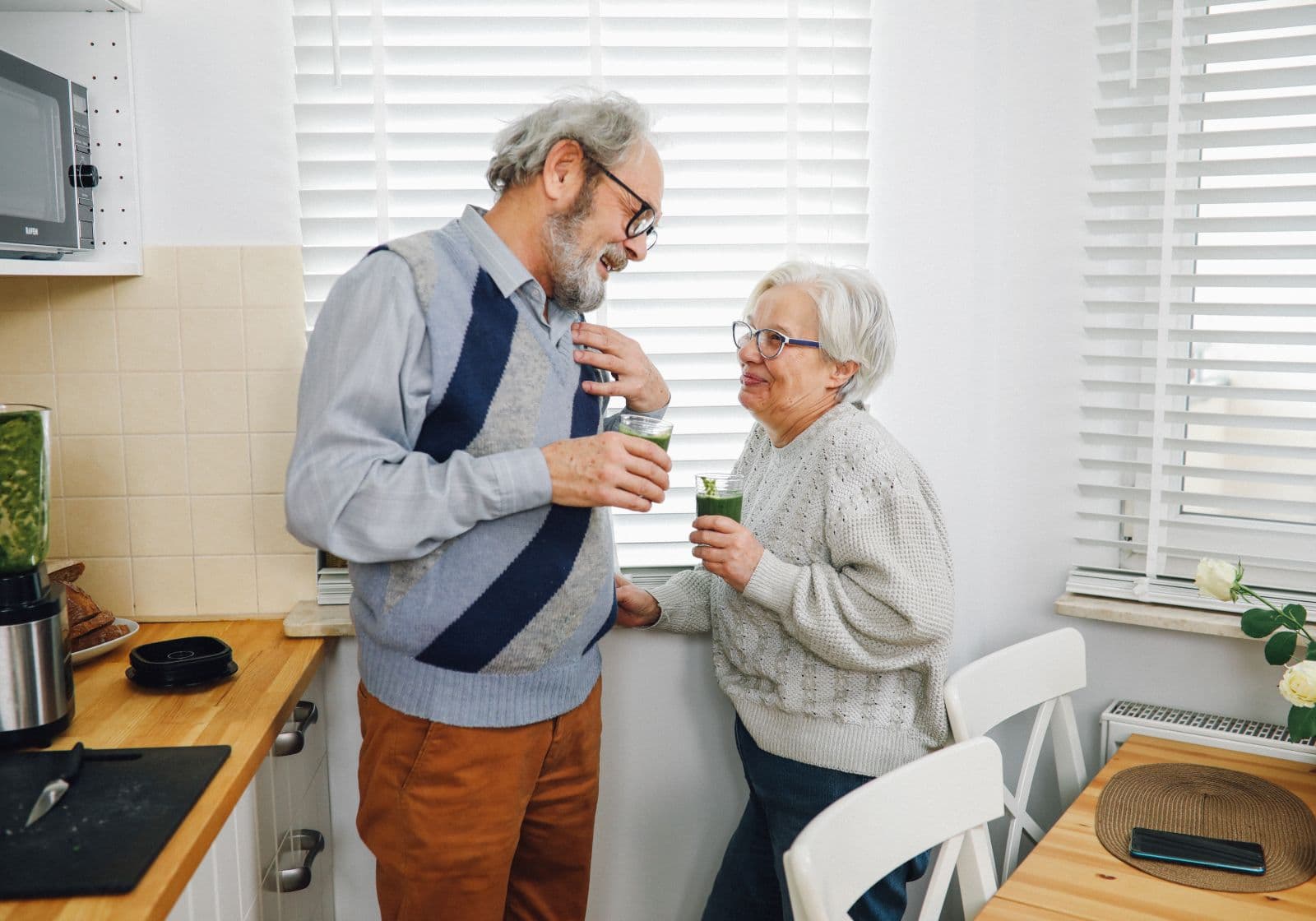 Ouder koppel praat samen in de keuken bij het raam